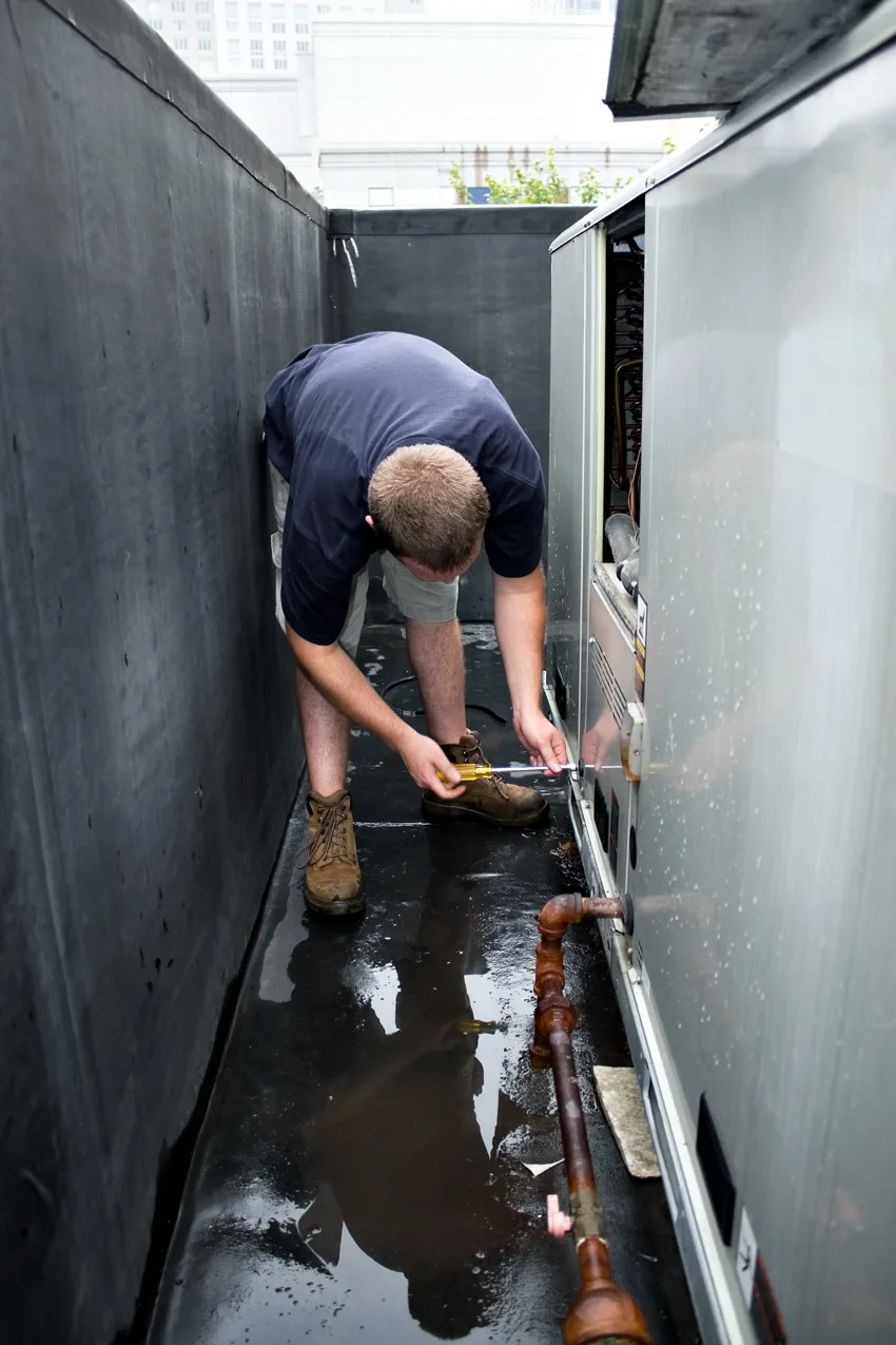 Technician servicing a large outdoor commercial air conditioning unit.